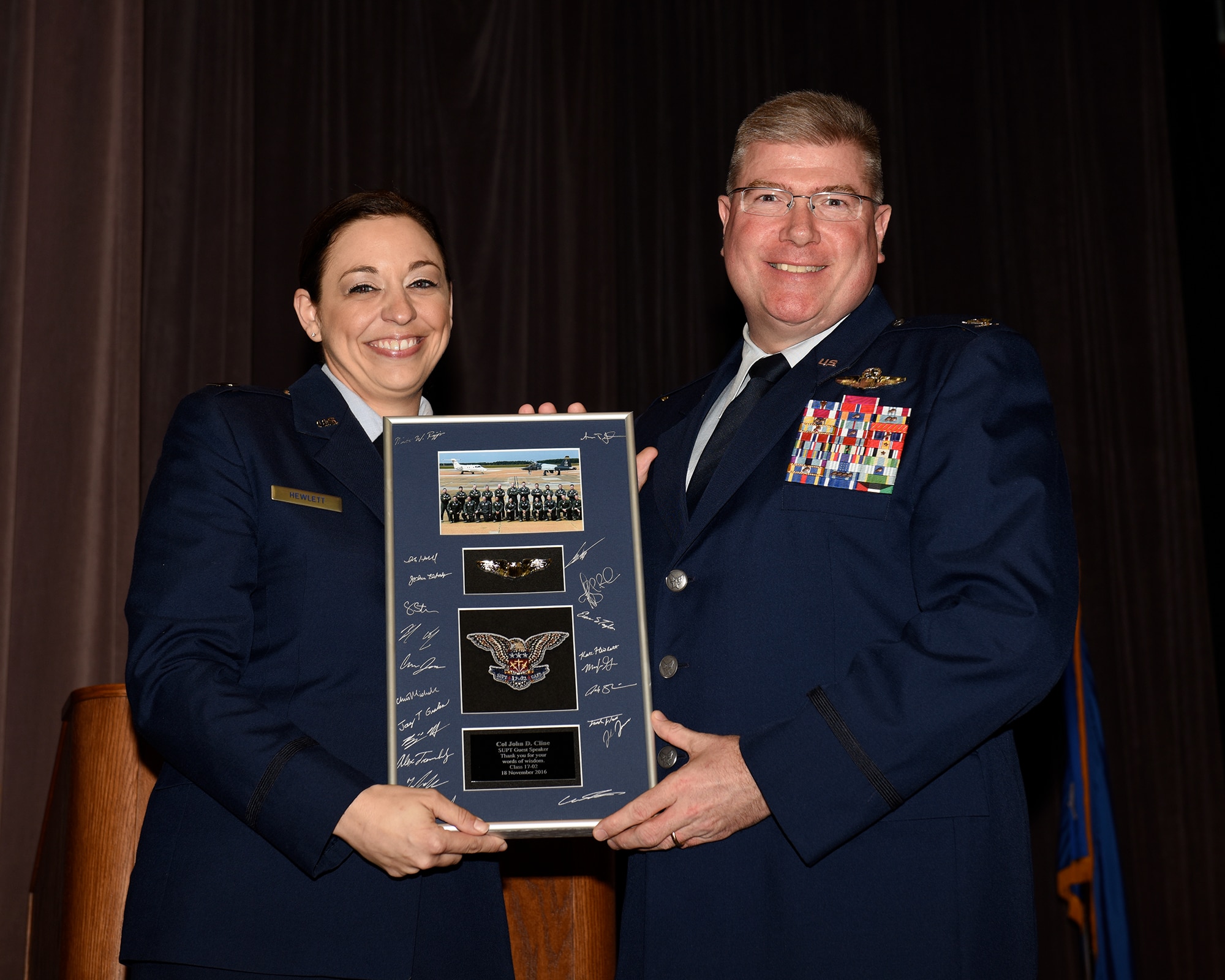 Capt. Katherine Hewlett, Specialized Undergraduate Pilot Training Class 17-02 Class Leader, presents a gift to Col. John Cline, Deputy Director of Operations, Headquarters Air Force Special Operations Command, Hurlburt Field, Florida, at the SUPT Class 17-02 graduation Nov. 18, 2016, at Columbus Air Force Base, Mississippi. Cline expressed his gratitude and pride for the newest graduates and spoke of how the training they received at Columbus AFB was their career foundation. (U.S. Air Force photo by Melissa Doublin)