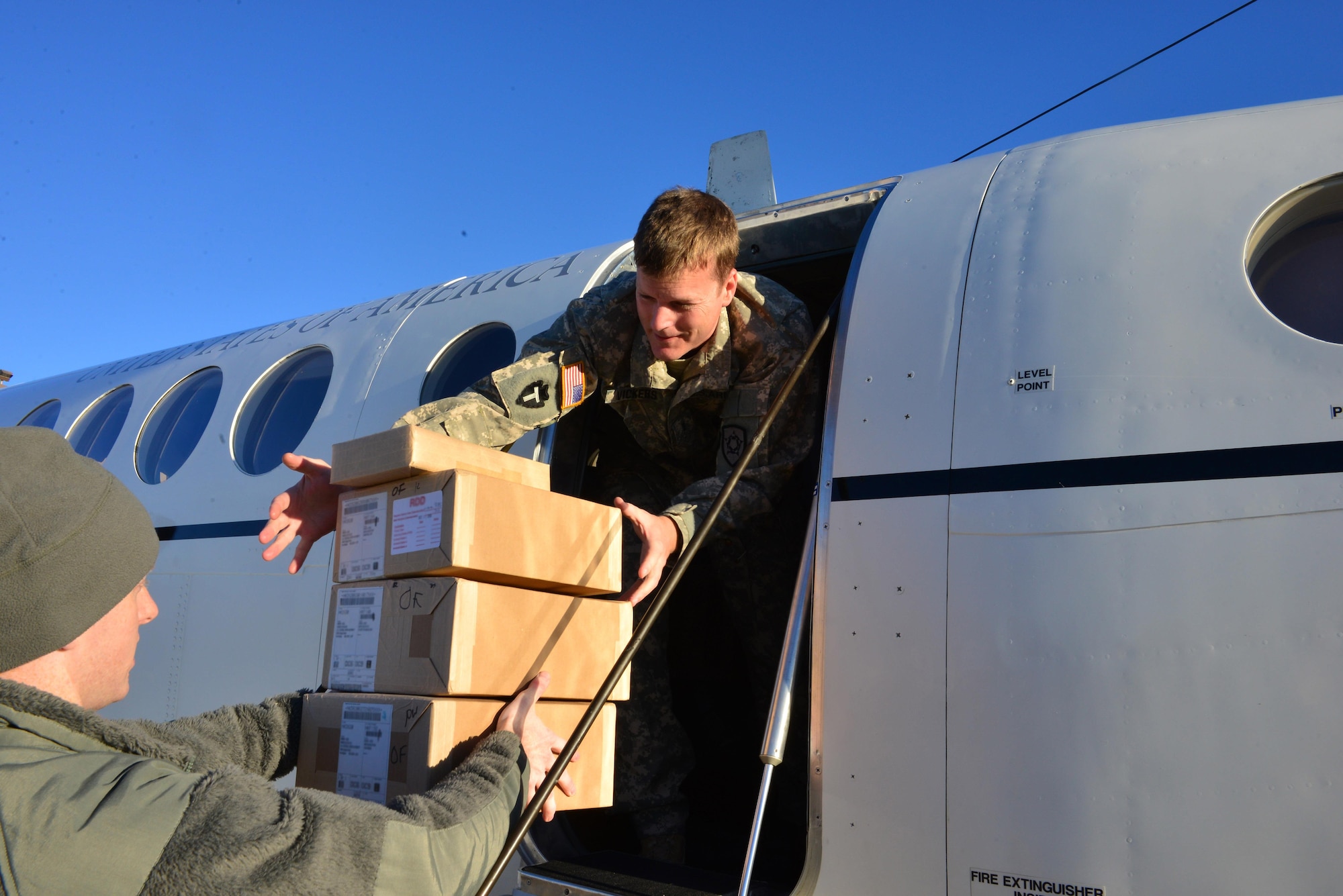 Chief Warrant Officer Richard Vickers, a pilot, helps load packages containing sensitive equipment on the Offutt flight line at Offutt Air Force Base, Neb., Nov. 16, 2016. Defense couriers move sensitive and top secret material globally for the Department of Defense and other government agencies. (U.S. Air Force photo/Senior Airman Rachel Hammes)