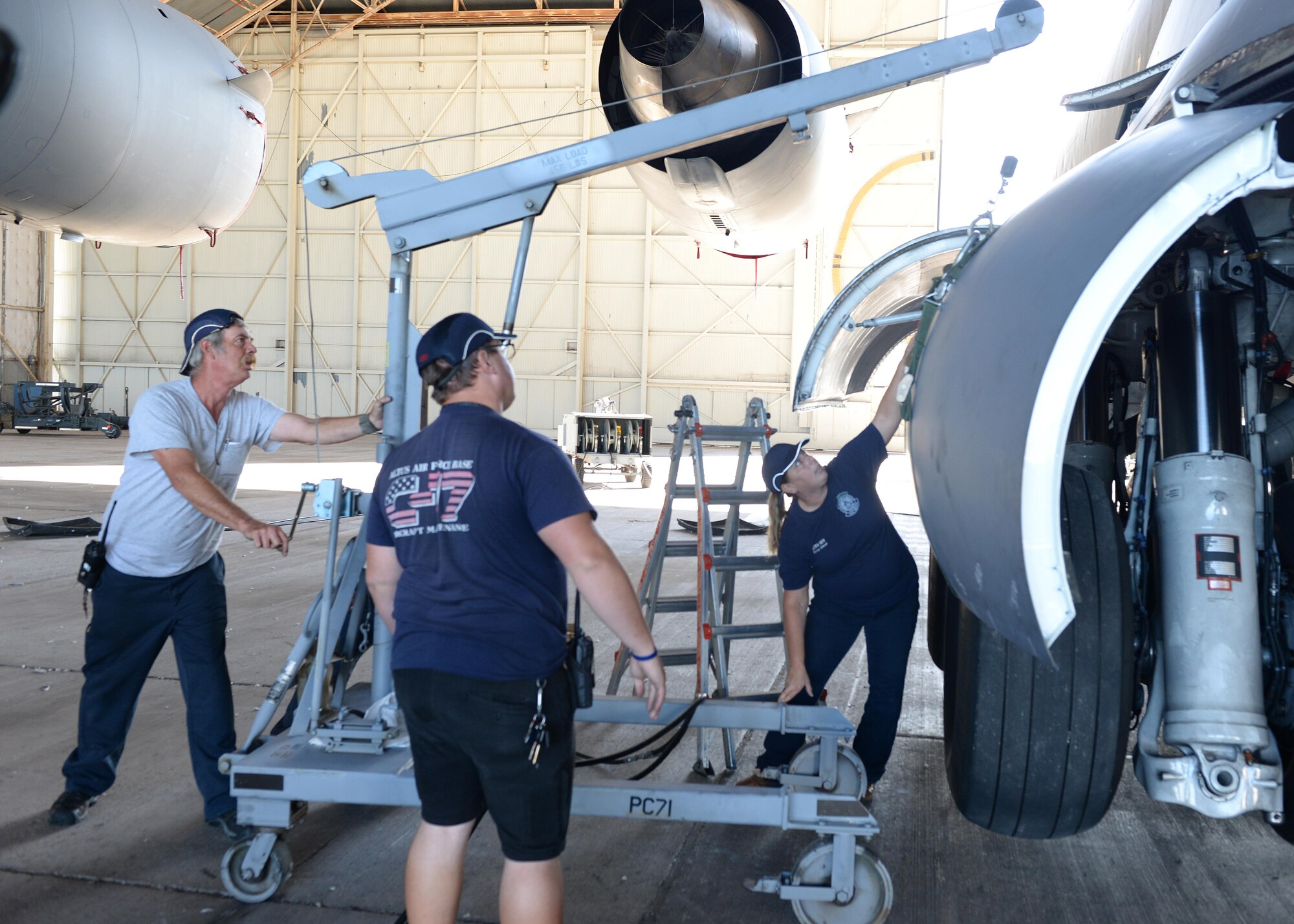 97th Maintenance Directorate aircraft maintainers, unhinge a landing gear cover, Sep. 28, 2016, at Altus Air Force Base, Okla. For the past 20 years the 97th MX has been a heavily comprised civilian work force that is responsible for maintaining Altus AFB’s aircraft. (U.S. Air Force photo by Airman 1st Class Cody Dowell/Released)