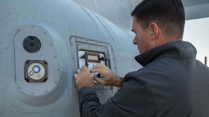 Jon Ayres attaches a countermeasure dispensing simulator to the side of a V-22 Osprey to assess the tactical aircraft protection system on the aircraft at Marine Corps Air Station New River, N.C., Nov. 17, 2016. Marine Medium Tilitrotor Squadron 365 (Reinforced) conducted the assessment to prepare for their upcoming deployment with the 24th Marine Expeditionary Unit. Ayres is a ALE- 47 program Navy Logistician with the fleet support team. 