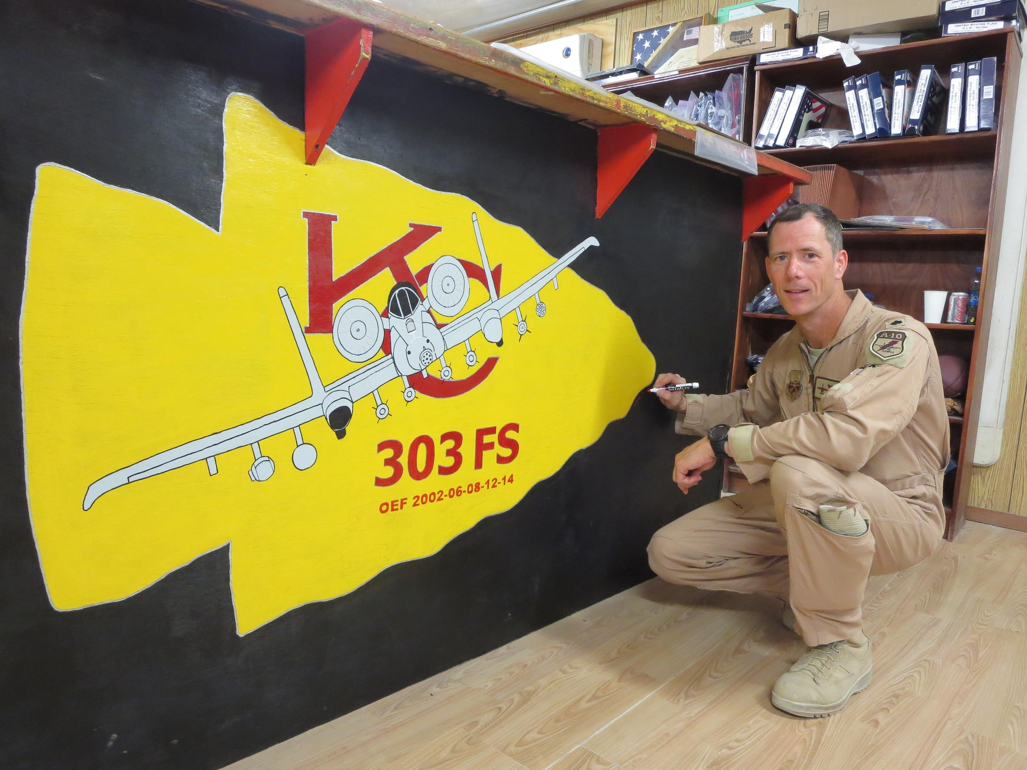 U.S. Air Force Lt. Col. John Marks smiles in front of his 303rd Fighter Squadron artwork at Bagram Air Base, Afghanistan, during Operation Enduring Freedom in 2014. The 303rd Fighter Squadron is attached to the 442d Fighter Wing, a Reserve wing located at Whiteman Air Force Base, Missouri. (Courtesy photo provide by Lt. Col. Marks)