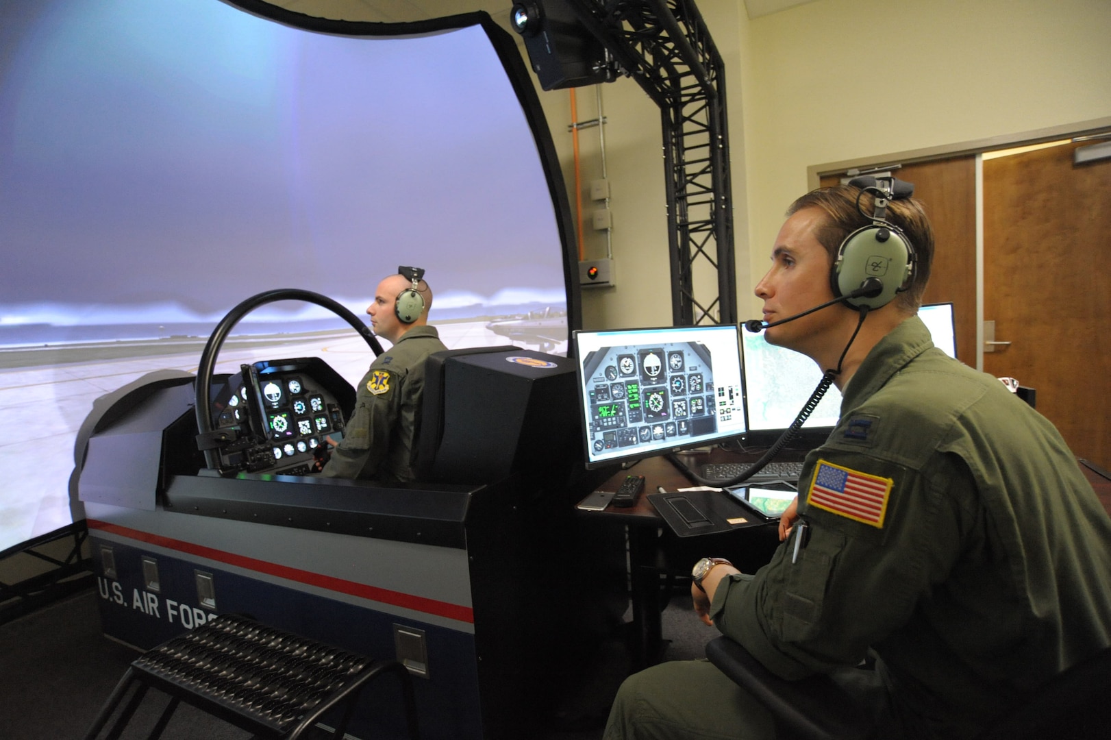 Capt. Mike, left, 558th Flying Training Squadron student, trains on a T-6 simulator, while Capt. Brandt, 558th FTS instructor, operates the instrument computer panel Nov. 7, at Joint Base San Antonio-Randolph.  The 558th FTS is the home of the Air Force's only undergraduate remotely piloted aircraft training program. 