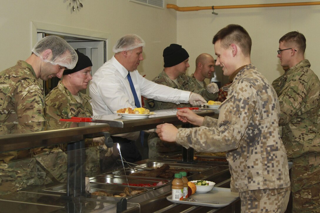 Leaders assigned to the 2nd Battalion, 503rd Infantry Regiment, 173rd Airborne Brigade, assist Latvian Defense Minister Raimonds Bergmanis as he serves Thanksgiving dinner to U.S. and Latvian troops at Camp Adazi, Latvia, Nov. 22, 2016. Army photo by Sgt. Lauren Harrah