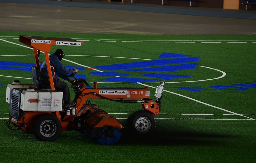 A contractor evens out the distribution of rubber pellets of the new sports field inside the Pride Hangar at Ellsworth Air Force Base S.D., Nov.21, 2016. The new sports turf will reduce the amount of rug-burn like injuries many Ellsworth members were getting while performing physical training workouts and playing sports on the old turf field. (U.S. Air Force photo by Airman 1st Class James L. Miller) 