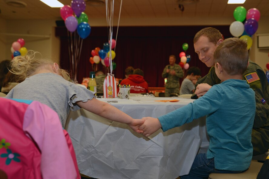 Airmen and their families hold hands during a prayer at the Hearts Apart dinner Nov. 17, 2016, at Joint Base Lewis-McChord, Wash. The dinner was hosted for Airmen and their families who are recently, currently or soon to be deployed or assigned to a temporary duty assignment. (U.S. Air Force photo/Senior Airman Jacob Jimenez) 