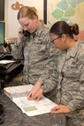 From left Airman 1st Class McKenzie Wolaver and Senior Airman Erika Santos, 5th Bomb Wing command post emergency actions officers, relay information through a secure phone line at Minot Air Force Base, N.D., Nov. 15, 2016. Controllers provide local data, such as, weather notifications and immediate response actions, to wing personnel to ensure they understand their is safe and knows their role during an emergency situation. (U.S. Air Force photo/Airman 1st Class Jessica Weissman)