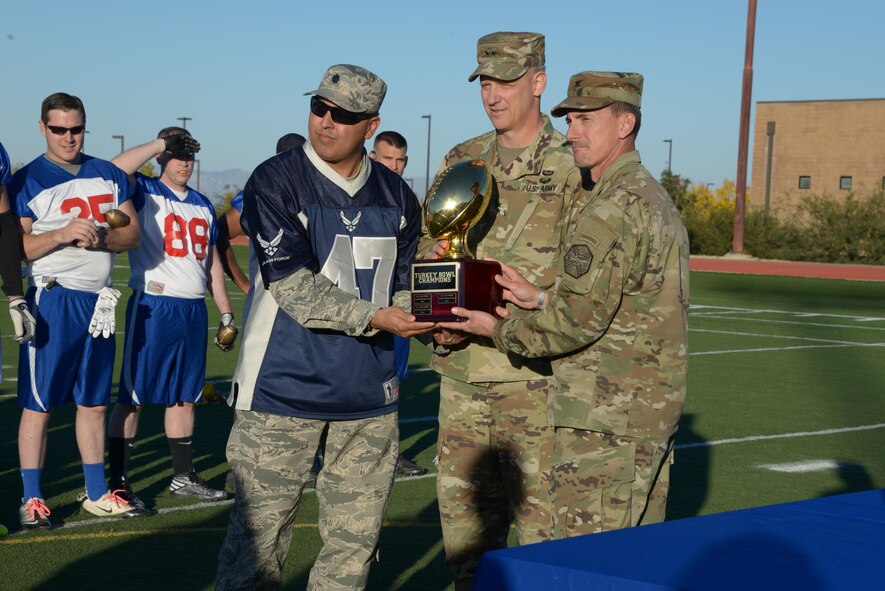 U.S. Army Maj. Gen. Scott Berrier, commanding general, U.S. Army Intelligence Center of Excellence and Fort Huachuca, and Col. Whit Wright, Fort Huachuca garrison commander, present U.S. Air Force Lt. Col. Marc Herrera, 355th Mission Support Group deputy commander, with the Turkey Bowl trophy at Fort Huachuca, Ariz., Nov. 18, 2016. The Turkey Bowl is a friendly annual flag football game between the Fort Huachuca Black Knights and the Davis-Monthan Air Force Base Mustangs. (U.S. Air Force photo by Senior Airman Betty R. Chevalier)