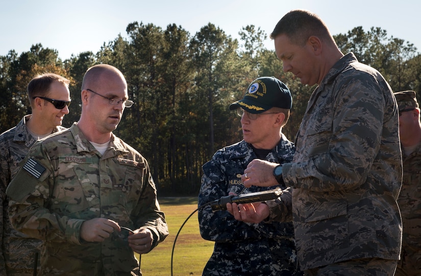 Tech. Sgt. Dwayne Ferugson, 628th Civil Engineer Squadron explosive ordnance disposal technician explains the differences of setting up electric circuits for demolition to U.S. Navy Capt. Robert Hudson and JB Charleston commander Col. Robert Lyman, during an EOD detonation here. The 628th CES EOD flight worked with local emergency management teams to safely dispose of explosives brought ashore by the tides of Hurricane Matthew in October. 