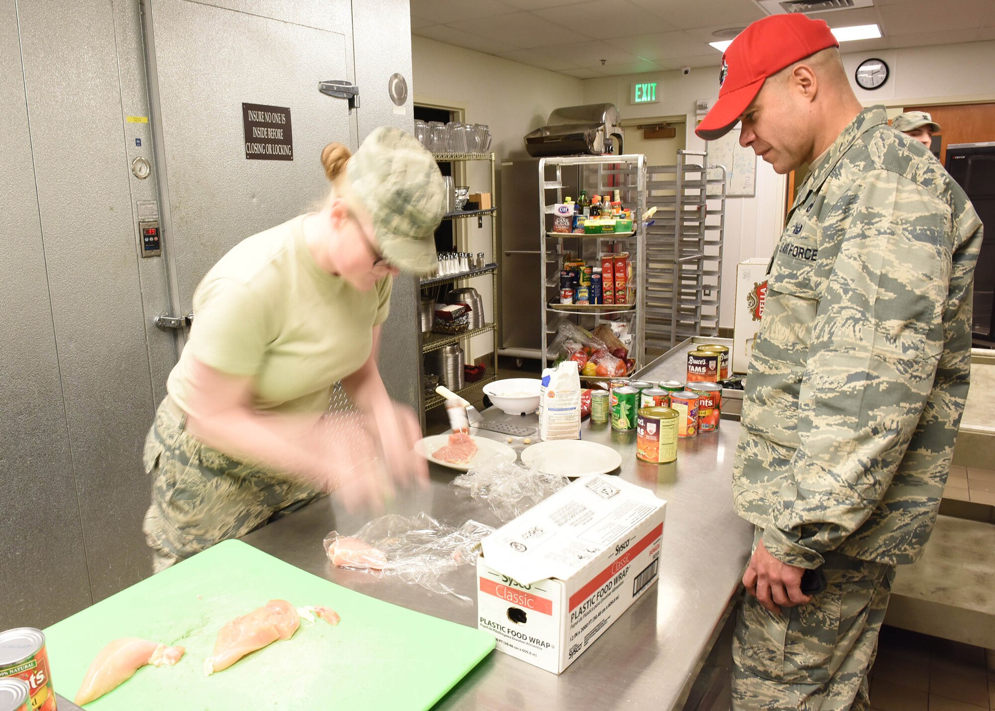Senior Airman Jessica Rugg, 341st Force Support Squadron missile field chef, tenderizes chicken as she participates in the Warrior Chef Competition as Col. Jose Rivera, 819th RED HORSE Squadron commander, as one of the judges, looks on, Nov. 22, 2016, at Malmstrom Air Force Base, Mont.  The quarterly event was held at the Grizzly Bend Recreation Center.  (U.S. Air Force photo/Jason Heavner)