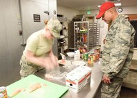 Senior Airman Jessica Rugg, 341st Force Support Squadron missile field chef, tenderizes chicken as she participates in the Warrior Chef Competition as Col. Jose Rivera, 819th RED HORSE Squadron commander, as one of the judges, looks on, Nov. 22, 2016, at Malmstrom Air Force Base, Mont.  The quarterly event was held at the Grizzly Bend Recreation Center.  (U.S. Air Force photo/Jason Heavner)