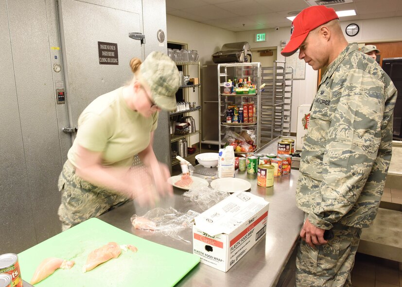 Senior Airman Jessica Rugg, 341st Force Support Squadron missile field chef, tenderizes chicken as she participates in the Warrior Chef Competition as Col. Jose Rivera, 819th RED HORSE Squadron commander, as one of the judges, looks on, Nov. 22, 2016, at Malmstrom Air Force Base, Mont.  The quarterly event was held at the Grizzly Bend Recreation Center.  (U.S. Air Force photo/Jason Heavner)
