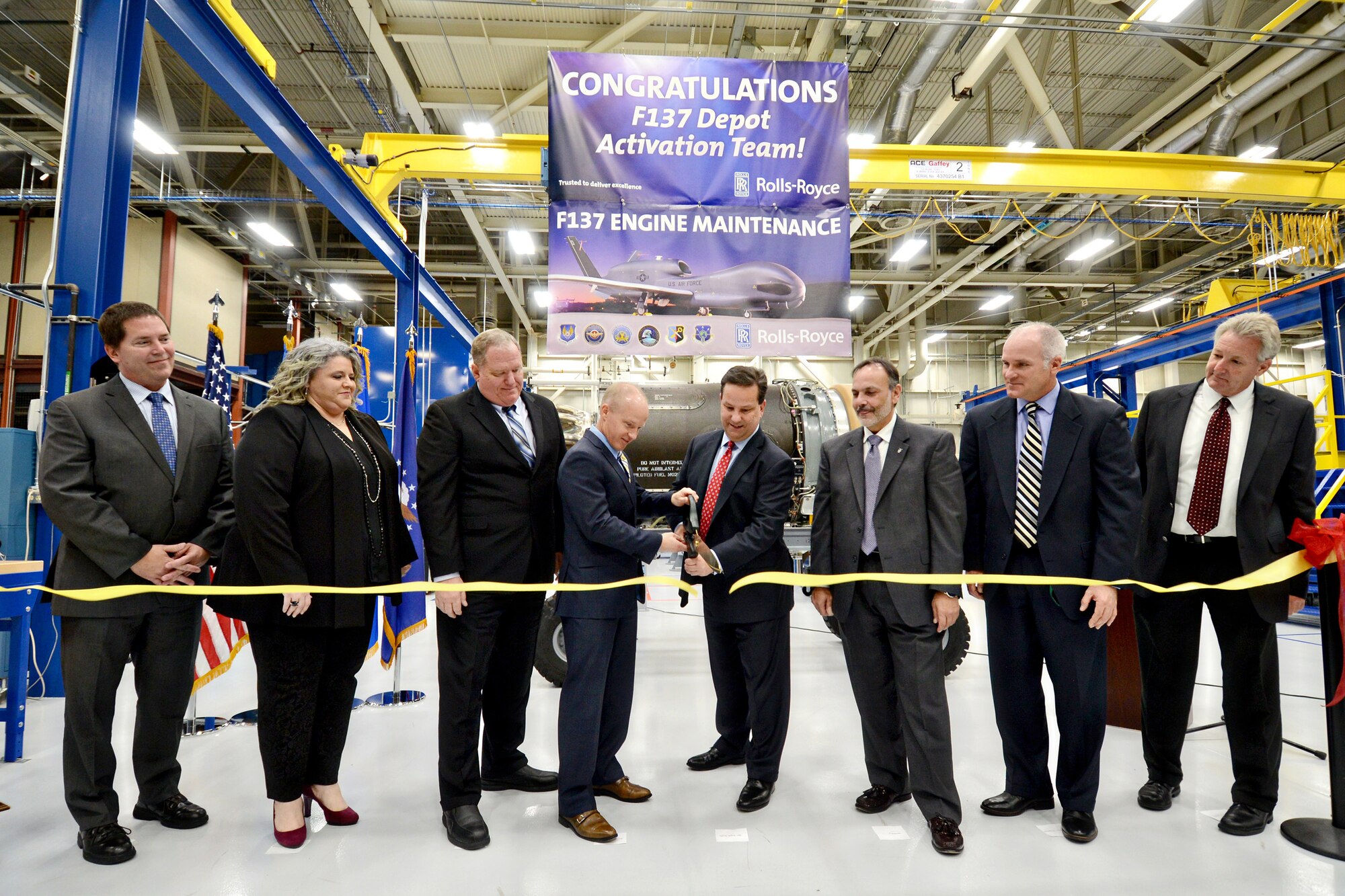 Phil Burkholder, president of Defense North America, Rolls-Royce, and Wade Wolfe, vice director of the Oklahoma City Air Logistics Complex, cut the ceremonial ribbon signifying the opening of the F137 engine maintenance line in Bldg. 3221 Nov. 15. Also present are three representatives with Rolls-Royce; Mr. Phil Burkholder, President, North America Rolls-Royce; Mr. Wade Wolfe, OC-ALC vice director; Ralph Garcia, director of Propulsion Directorate; Robert Helgeson, director of the 76th Propulsion Maintenance Group; and Mike Opela, director of the 544th Propulsion Maintenance Squadron. (Air Force photo by Kelly White)