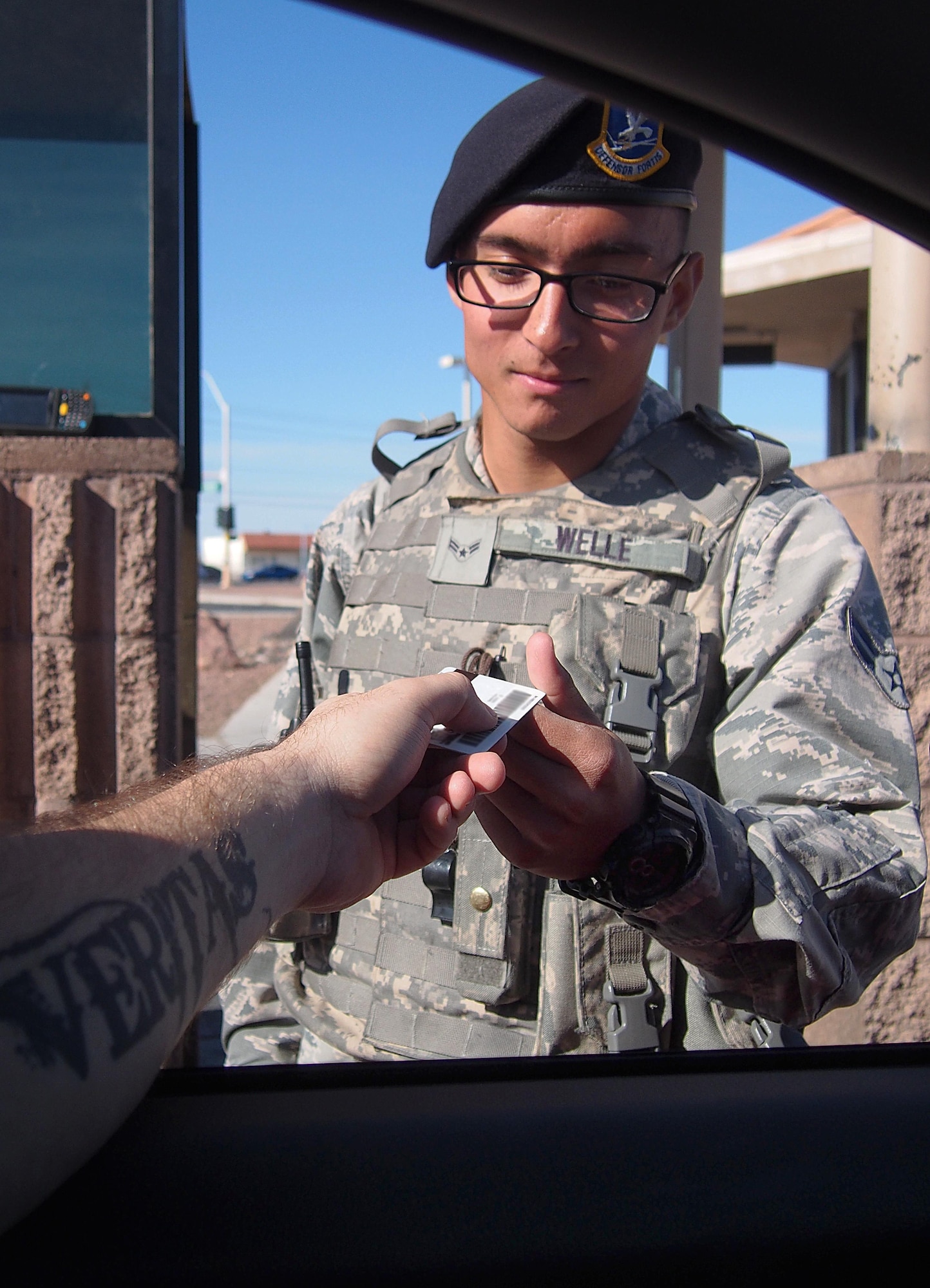 Airman 1st Class Logan Welle, 99th Security Forces Squadron entry controller, accepts an identification card for access to Nellis Air Force Base, Nev., Nov. 23. For the Pass & ID office, some customers were unable to receive an access badge for the base following approval notification. Since then, the office went through a six month continuous process improvement to where customers can now show up at the front gate to request an access badge. (U.S. Air Force photo by Senior Airman Rachel Loftis/Released) 