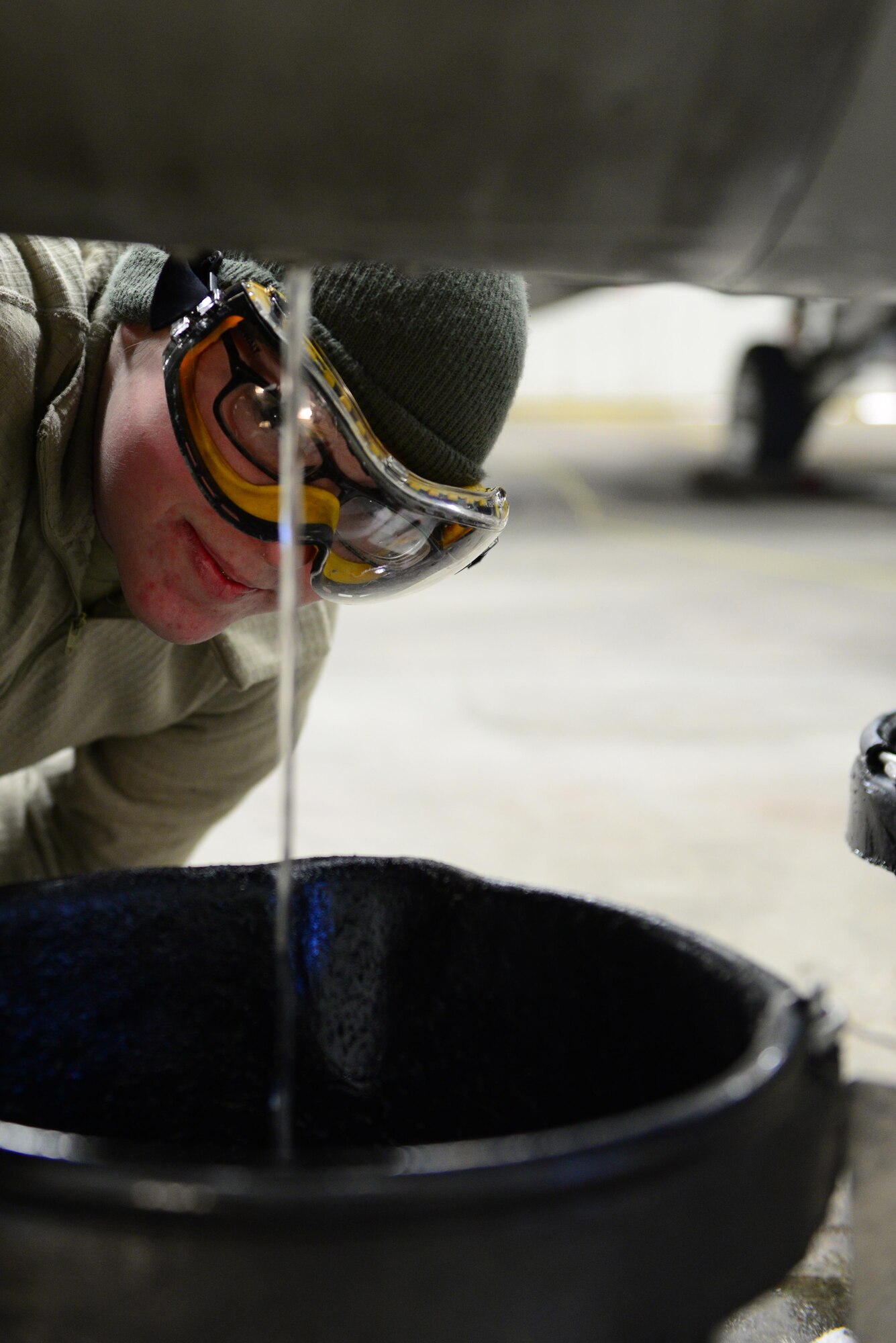 U.S. Air Force Senior Airman Jerri Addison, a 354th Aircraft Maintenance Squadron crew chief, watches fuel empty from an F-16 Fighting Falcon fuel tank into a bucket Nov. 22, 2016, at Eielson Air Force Base Alaska. The fuel was emptied into buckets and moved to another tank to be reused later. (U.S. Air Force photo by Airman Eric M. Fisher)