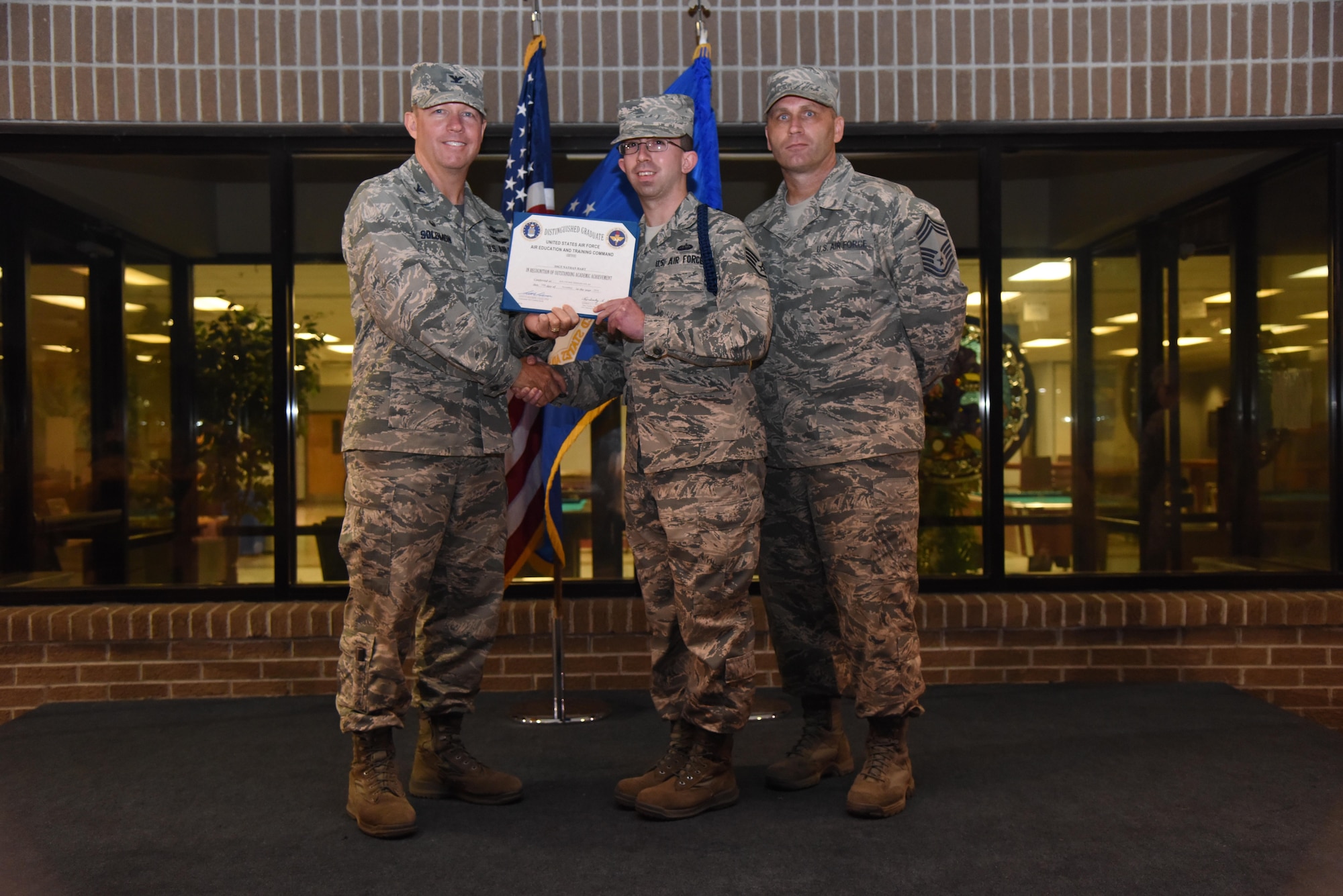 Staff Sgt. Nathan Hart, 334th Training Squadron military training leader, receives a distinguished graduate certificate from Col. Scott Solomon, 81st Training Group commander, and Chief Master Sgt. Anthony Fisher, 81st TRG chief, flag during a MTL graduation ceremony at Keesler Air Force Base, Miss., Nov. 18, 2016. The graduating students were the first class to attend the revised MTL course which includes Human Behavior and the Profession of Arms Center of Excellence training. (U.S. Air Force photo by Kemberly Groue)