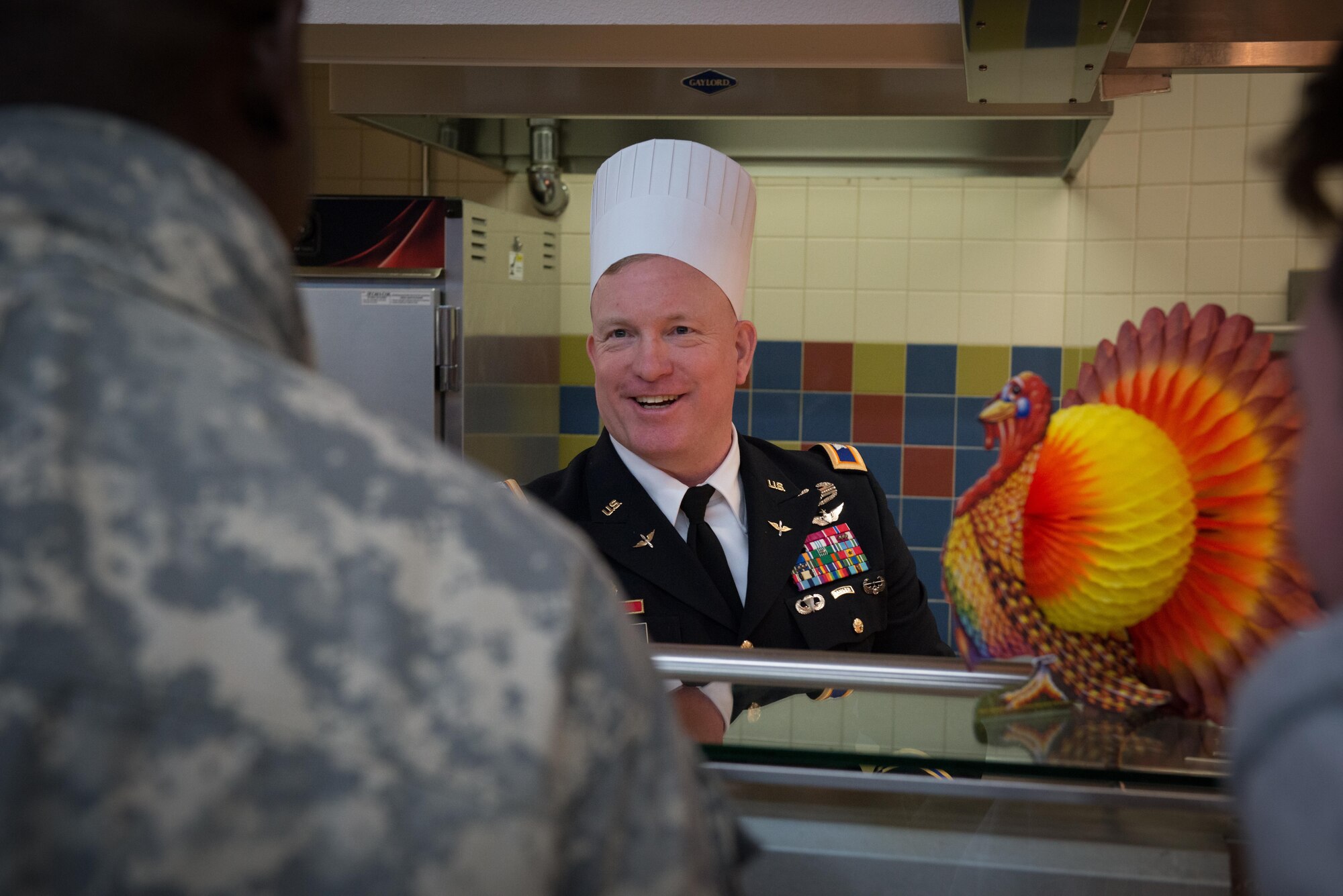 Army Col. Adam Lange, 673d Air Base Wing deputy commander, serves up a dish loaded with food to a Joint Base Elmendorf-Richardson Soldier Nov 23 at the Wilderness Inn Dining Facility. As a matter of tradition, every year, base leadership serve the Soldiers and Airmen of JBER a thanksgiving meal. 