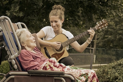 U.S. Air Force Staff Sgt. Carrie Gatz, an instrumentalist with the 566th Air Force Band, Illinois Air National Guard, plays guitar for a hospice patient at her civilian job Sept. 11, 2013. Gatz has served in the Air National Guard since 2004. 