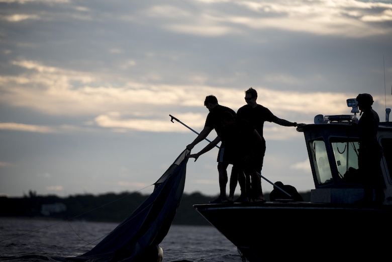 U.S. Air Force Airmen from the 320th Special Tactics Squadron retrieve parachutes after an early morning long-distance jump into the Pacific Ocean Nov. 22, 2016. The 320th STS Airmen conducted long-range jump training from a C-17 Globemaster III after returning from a previous training mission. (U.S. Air Force photo by Senior Airman Omari Bernard/Released)