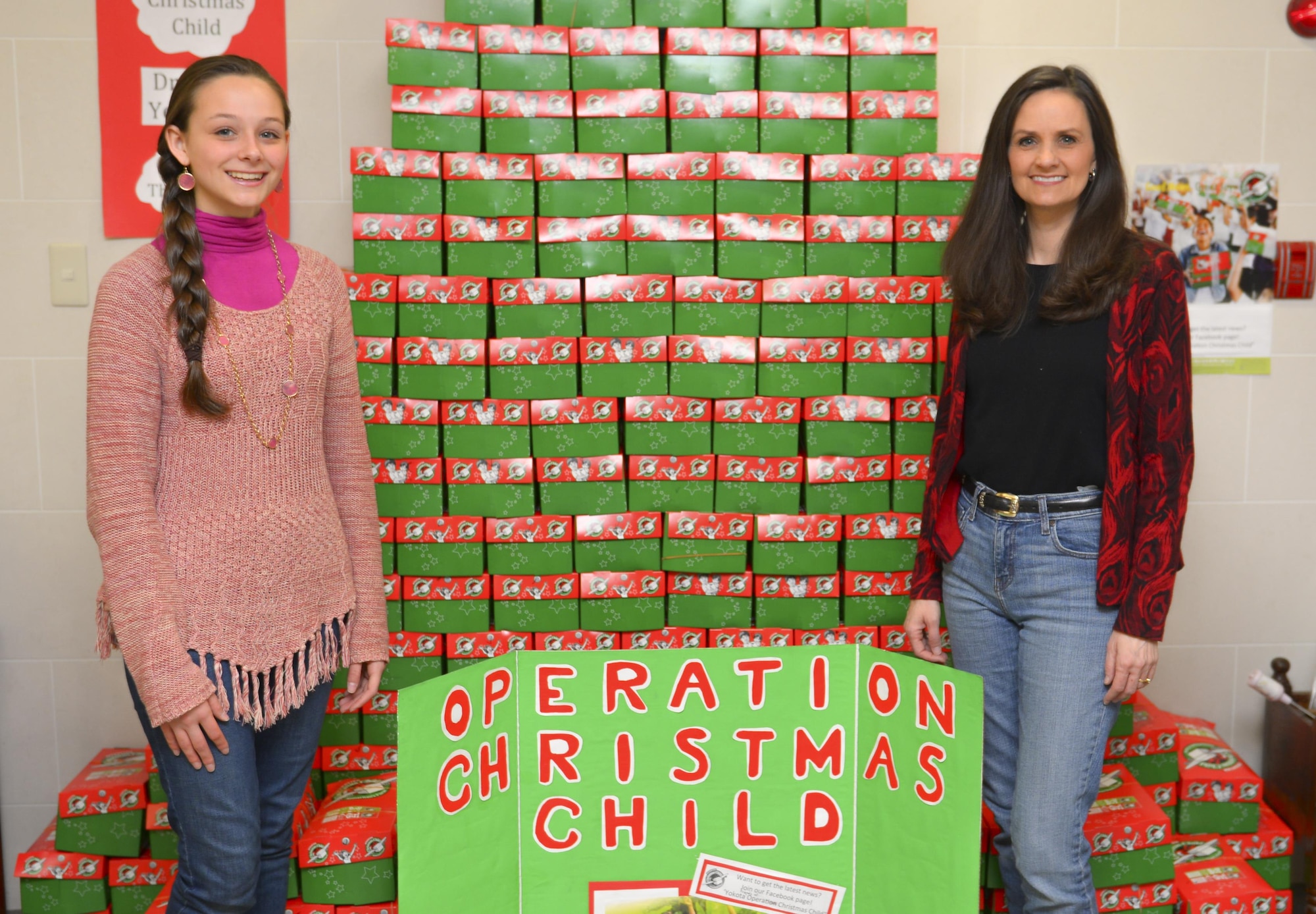 Drew Jernigan, right, and daughter, Hunter Grace, coordinators for Yokota’s Operation Christmas Child initiative, pose for a photo in front of gifts for children at Yokota Air Base, Japan, Nov. 10, 2016. The Jernigans collect items year round to send to disadvantaged children around the world through OCC, providing Yokota personnel and families with a way to give back during the holiday season. (U.S. Air Force photo by Airman 1st Class Elizabeth Baker/Released)