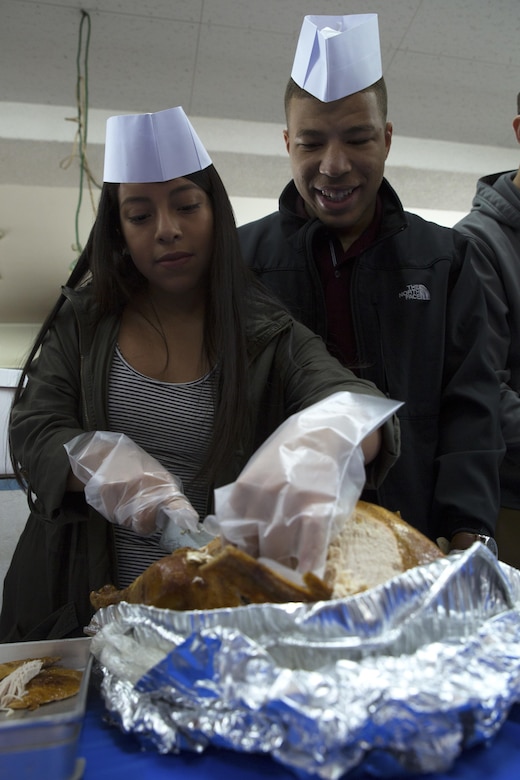 Lance Cpl. Lucero Ventura, left, and Lance Cpl. Ladwaune Edwards carve a turkey before a special Thanksgiving meal served to Okinawa patrons at the Promise Keepers Homeless Shelter Nov. 24 in Urasoe City, Okinawa, Japan. The event strengthened the relationship between service members and Okinawa residents by allowing them to volunteer in the local community and provide food to the needy. Service members from Camp Kinser gathered to serve a vast array of Thanksgiving dishes and eat with the patrons. Ventura is a warehouse clerk with Supply Battalion, Combat Logistics Regiment 35, 3rd Marine Logistics Group, III Marine Expeditionary Force, and is a Los Angeles, California, native. Edwards is a warehouse clerk with 3rd Supply Battalion and is a Jacksonville, North Carolina, native. (U.S. Marine Corps photo by Cpl. Janessa K. Pon)
