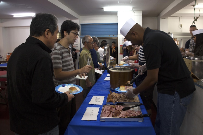 Service members from Camp Kinser serve a special Thanksgiving meal to Okinawa residents at the Promise Keepers Homeless Shelter Nov. 24 in Urasoe City, Okinawa, Japan. The event provided service members with the opportunity to positively impact the Okinawa community through food, fellowship and holiday celebration. During the dinner, Okinawan patrons and service members enjoyed a traditional Thanksgiving meal together. (U.S. Marine Corps photo by Cpl. Janessa K. Pon)