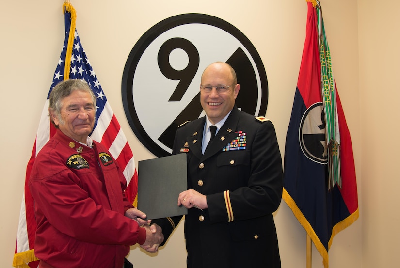 (Left) 94th Infantry Division Historical Society Secretary John Clyburn hands a Memorandum of Agreement to 94th Training Division Assistant Division Commander Col. John Aarsen at the division's headquarters at Fort Lee, Virginia, Nov. 21, 2016. According to the MOA, Aarsen promises the division will take good care of the society's flag. Clyburn took part in the flag transfer event, in which he and others from the society handed over their colors to Aarsen.