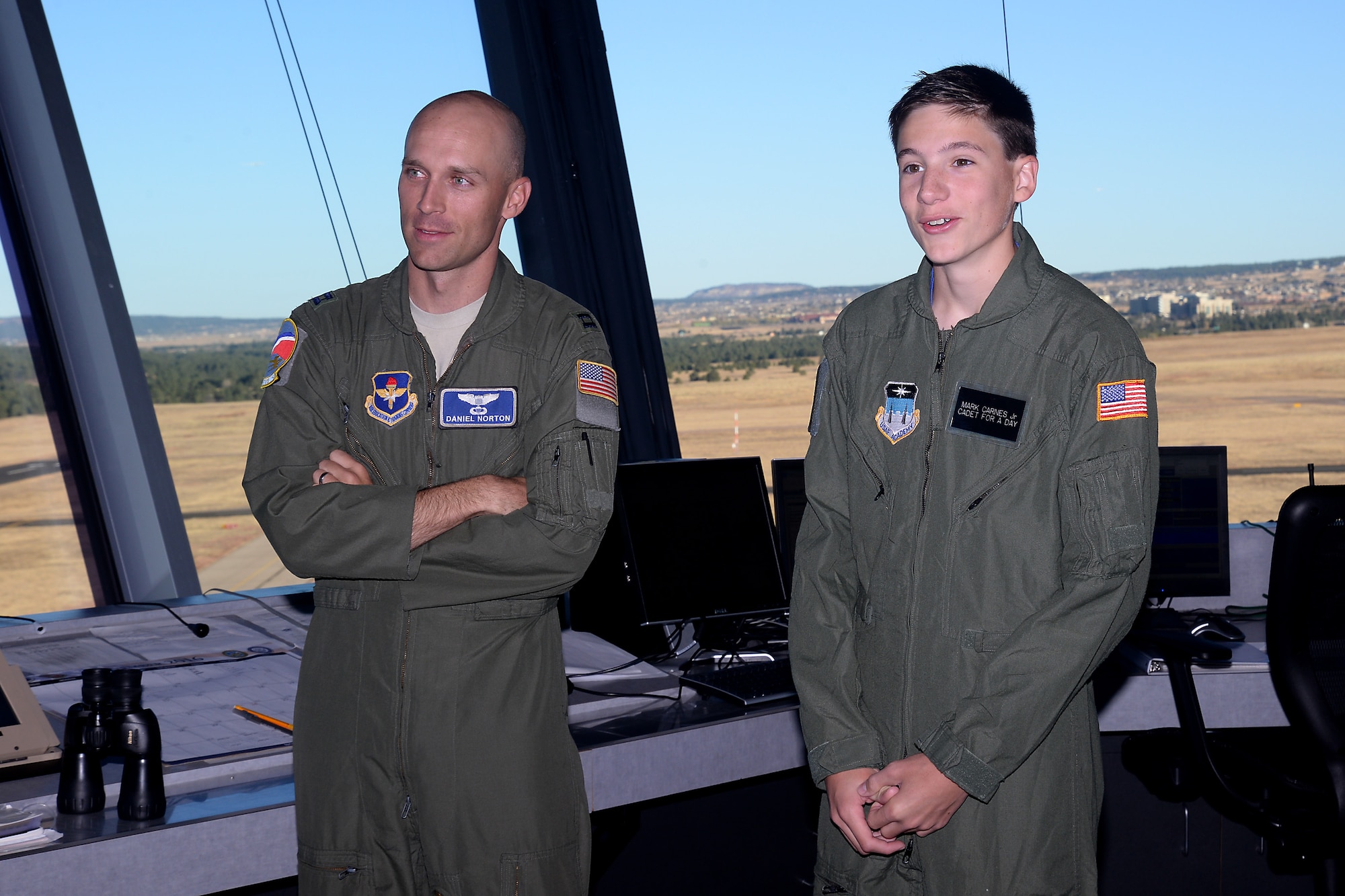 Mark Carnes, the U.S. Air Force Academy's latest Cadet for a Day, and Capt. Daniel Norton, look out the control tower windows at the Academy airfield, Nov. 10, 2016. The Academy has teamed up with the Make a Wish Foundation to help children with serious medical conditions achieve their dreams of becoming an Academy cadet, through the Cadet for a Day Program. Norton is the flight commander for the Cadet Instructor Pilot Upgrade Program for the 94th Flying Training Squadron. (U.S. Air Force photo/Darcie Ibidapo)