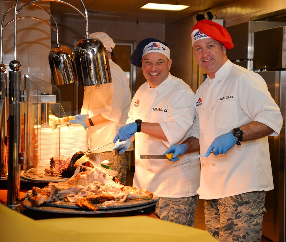 U.S. Air Force Brig. Gen. Mark Slocum, right, U.S. Air Forces in Europe-United Kingdom commander, and U.S. Air Force Col. Robert Hoskins, 100th Mission Support Group commander, pose for a photo as they serve turkey and ham Nov. 24, 2016, at the Gateway Dining Facility on RAF Mildenhall, England. The special meal was prepared in celebration of Thanksgiving and fed many Airmen and civilians from around Team Mildenhall. (U.S. Air Force photo by Karen Abeyasekere)