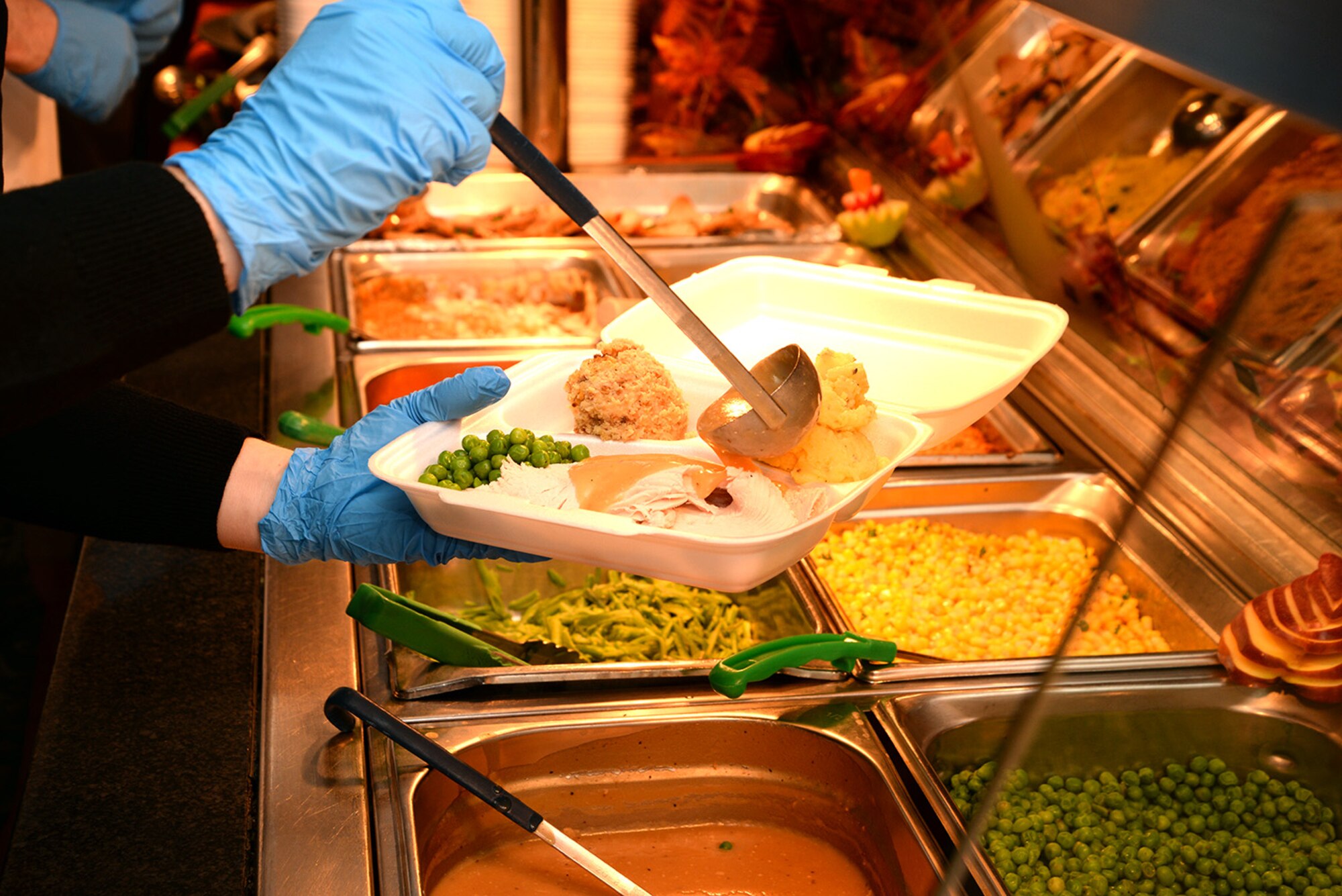Thanksgiving lunch is piled into a take-out container for an Airman Nov. 24, 2016, at the Gateway Dining Facility on RAF Mildenhall, England. Team Mildenhall leadership and their spouses joined with the dining facility staff to provide Airmen the opportunity to enjoy Thanksgiving away from home. (U.S. Air Force photo by Karen Abeyasekere) 