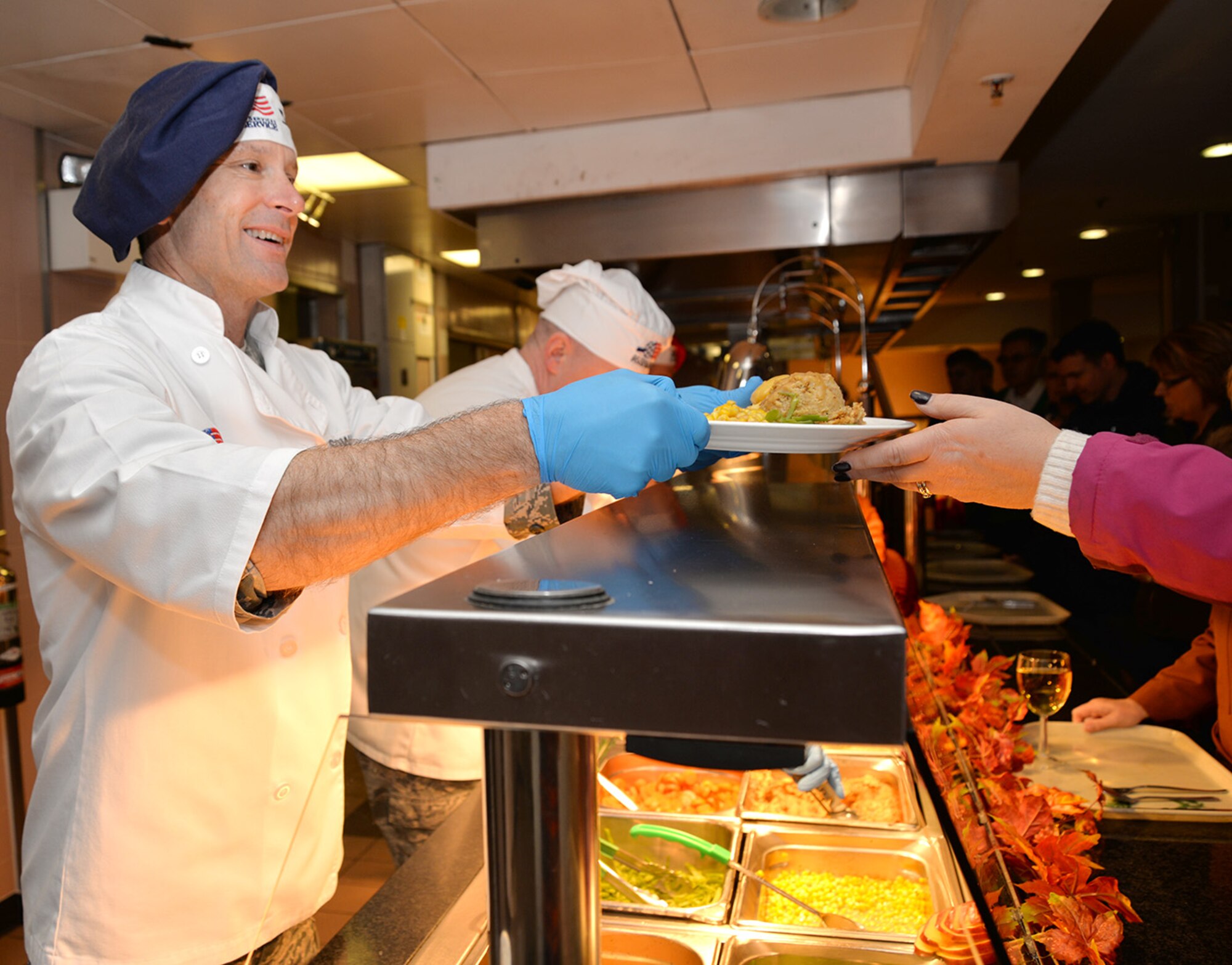 U.S. Air Force Col. Matthew Smith, left, 352nd Special Operations Wing commander, chats to a customer as he serves her food Nov. 24, 2016, at the Gateway Inn on RAF Mildenhall, England. The special meal was prepared in celebration of Thanksgiving and fed many Airmen and civilians from around Team Mildenhall. (U.S. Air Force photo by Karen Abeyasekere)