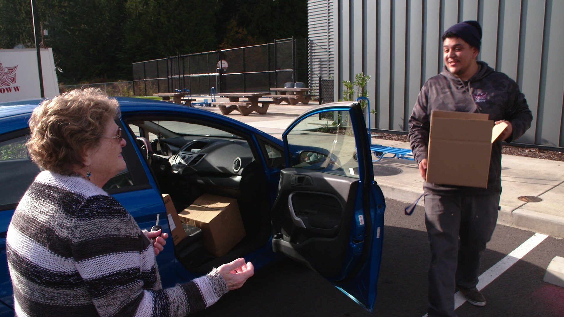 Vicki White (left) receives a box of fruits and vegetables at the Small Tribes of Western Washington’s food distribution site at the Shoalwater Bay Reservation. Photo by Peter Kent 