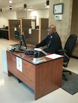 Defense Supply Center Richmond Welcome Center receptionist Michael Abraham readies to receive the next customer and issue a ticket using the new Visitor Management System.