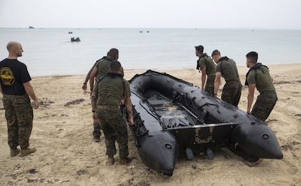 Marines from 3d Reconnaissance Battalion, 3d Marine Division, III Marine Expeditionary Force, carry a rubber inflatable raft into the water to begin the "boating" station on Camp Schwab, Okinawa during their annual Warrior Challenge, Nov. 25, 2016. This event honors fallen Marines in the battalion and consists of nine stations to challenge the Marines mentally and physically. 