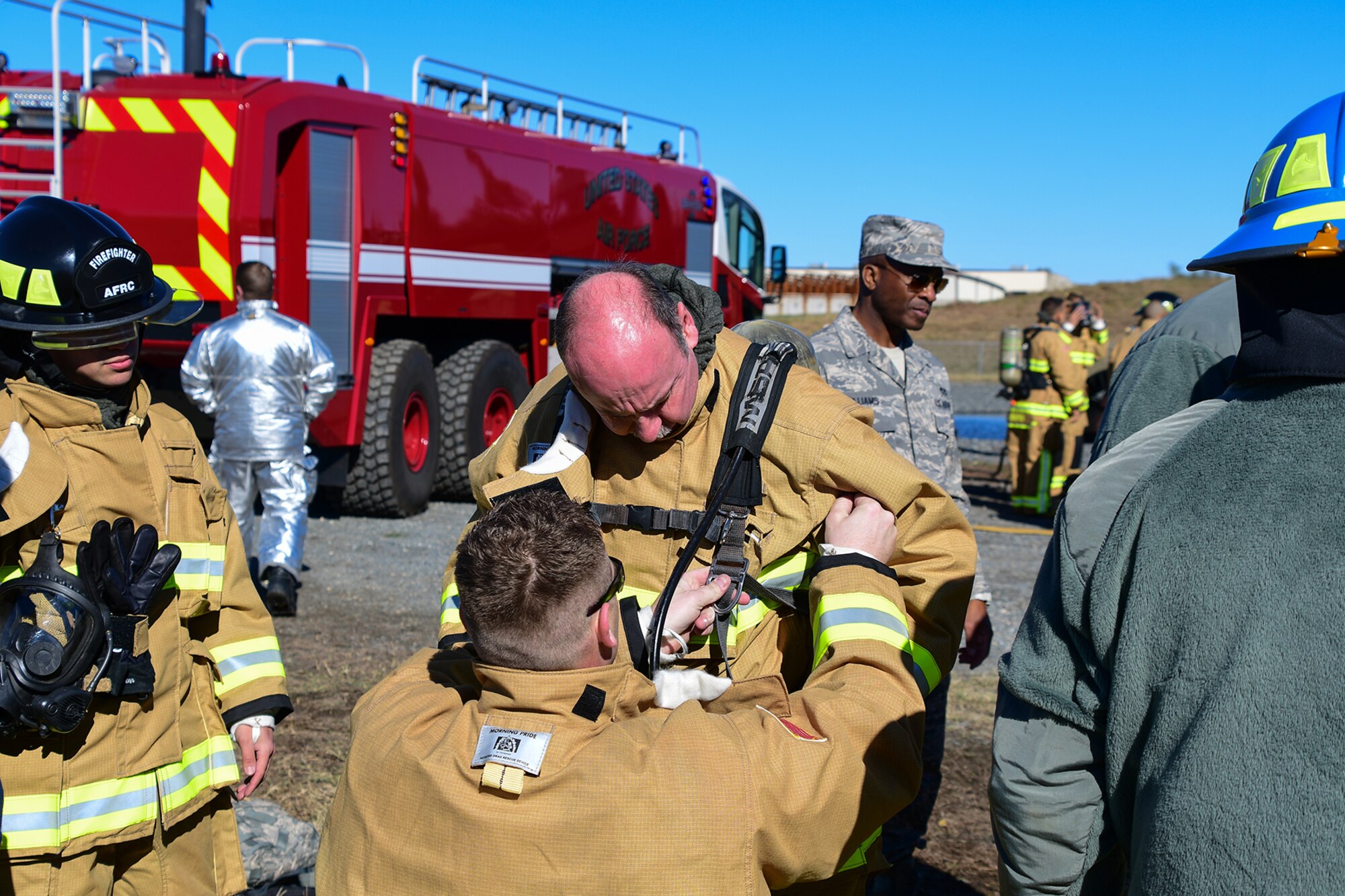 U.S. Air Force Chief Master Sgt. Apolinar Lopez, 307th Civil Engineering Squadron, gets assistance suiting up in fire gear on November 19, 2016, Barksdale Air Force Base, La. Lopez participated in a live fire practice where the fire department practices putting out fire on a mock aircraft. (U.S. Air Force photo by Master Sgt. Laura Siebert/ Released)