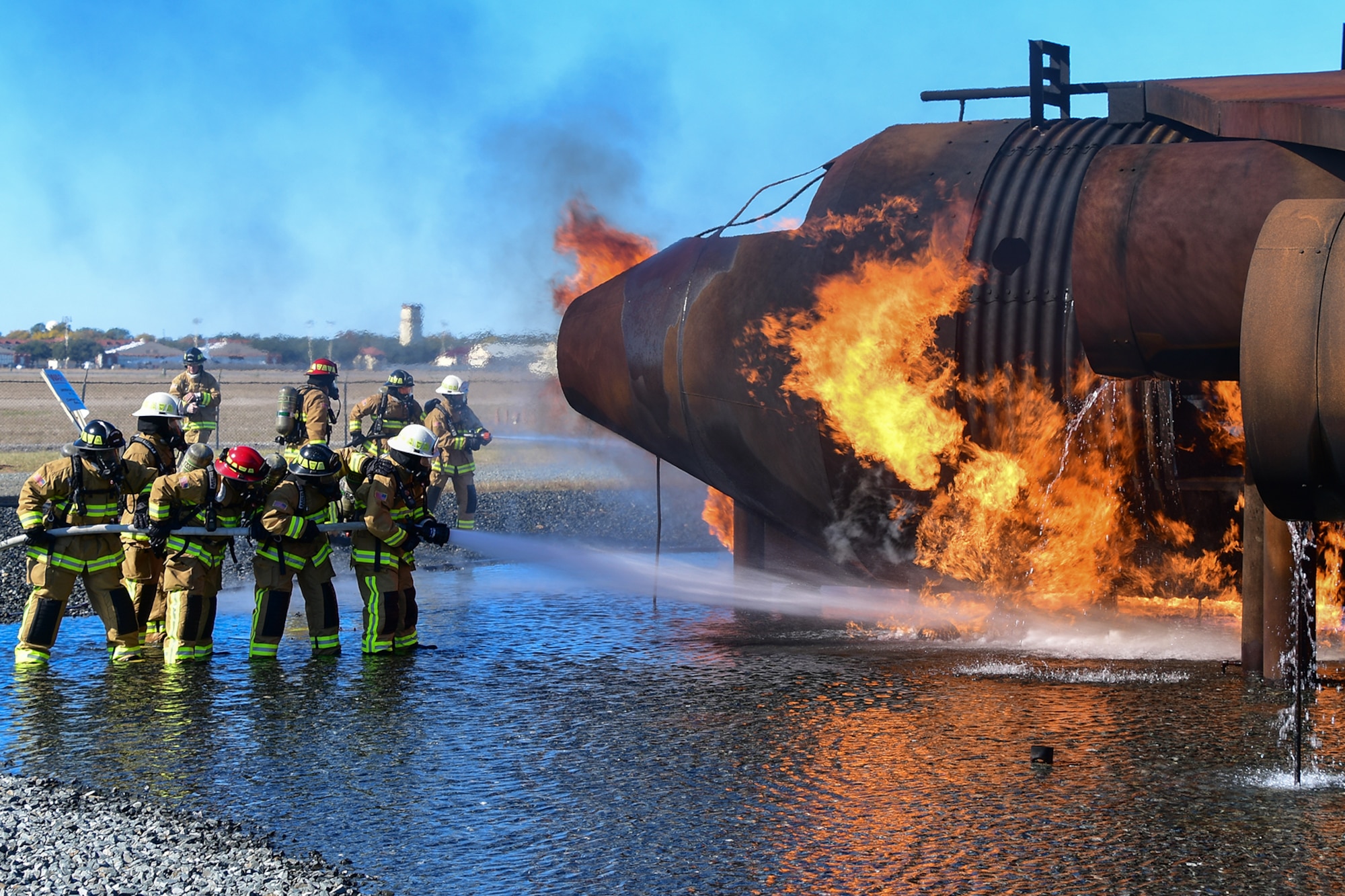Members of the 307th Civil Engineering Squadron practice fighting fire on a mock aircraft on Nov. 19, 2016, Barksdale Air Force Base, La. The fire is fueled by liquid propane and the water is contained in a containment pit. (U.S. Air Force photo by Master Sgt. Laura Siebert/ Released)