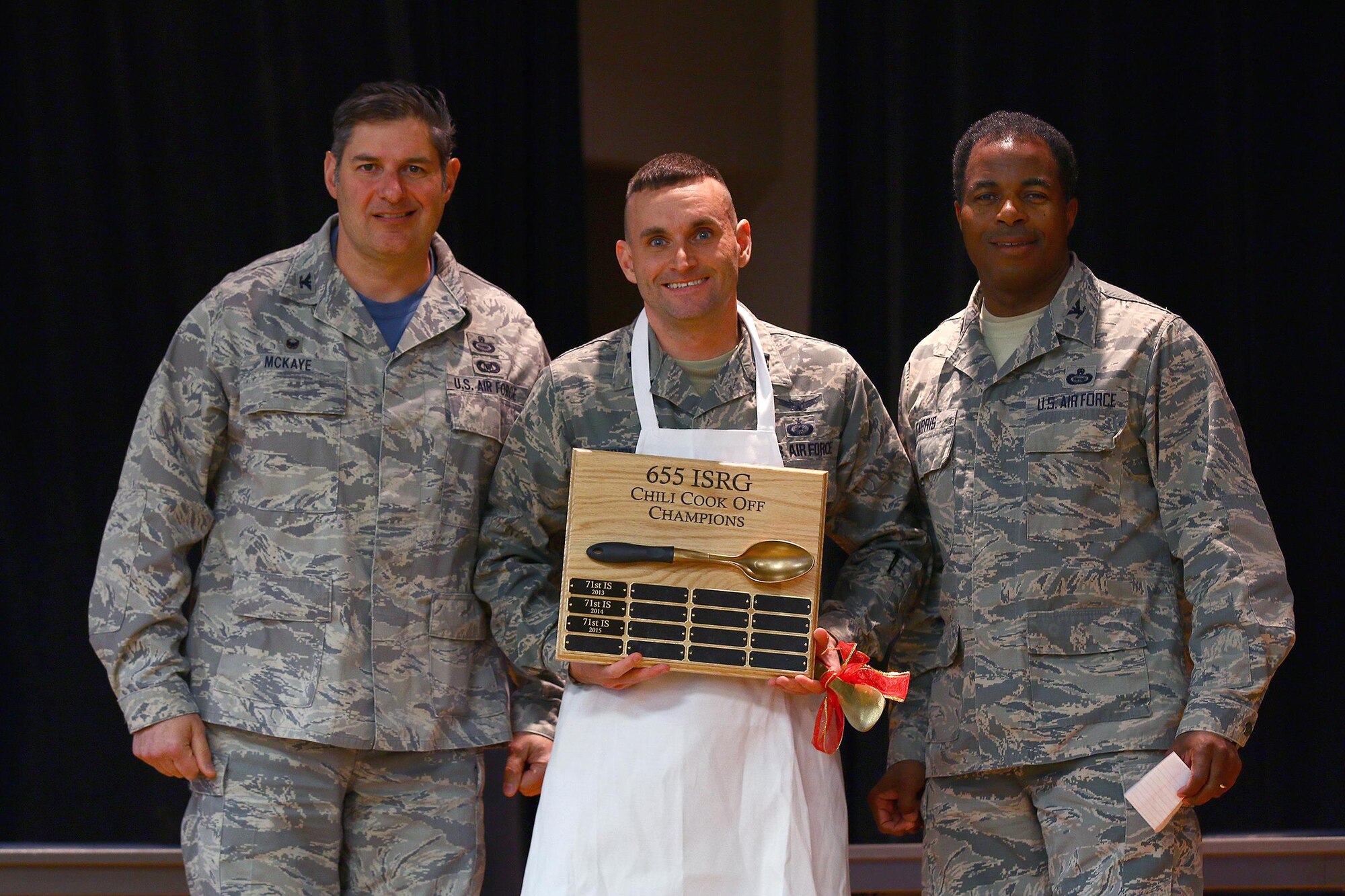Capt. James Spindler, 64th Intelligence Squadron, is the winner of the 2016 655th Intelligence, Surveillance and Reconnaissance Group Chili Cook-Off at the USO here Nov. 19, 2016. The captain received his apron award from Col. John D. McKaye, 655th ISRG commander (left) and Col. Lonnie Garris, III, 655th ISRG deputy commander. Capt. Spindler’s chili won in the ‘Best Overall’ category. The other three categories judged were: spiciest, white chili and most creative. (U.S. Air Force photo /Tech. Sgt. Patrick O’Reilly)