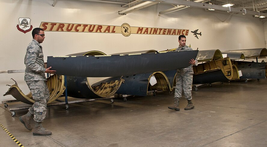 (From left) Senior Airmen Mikal Joyce and Jan Nazario, 5th Maintenance Squadron aircraft structural maintenance journeymen, carry a cowling at Minot Air Force Base, N.D. Oct. 27, 2016. These Airmen use various methods like sanding, corrosion and tubing to either build or install replacement parts for an aircraft. (U.S. Air Force photo/Airman 1st Class Jonathan McElderry)