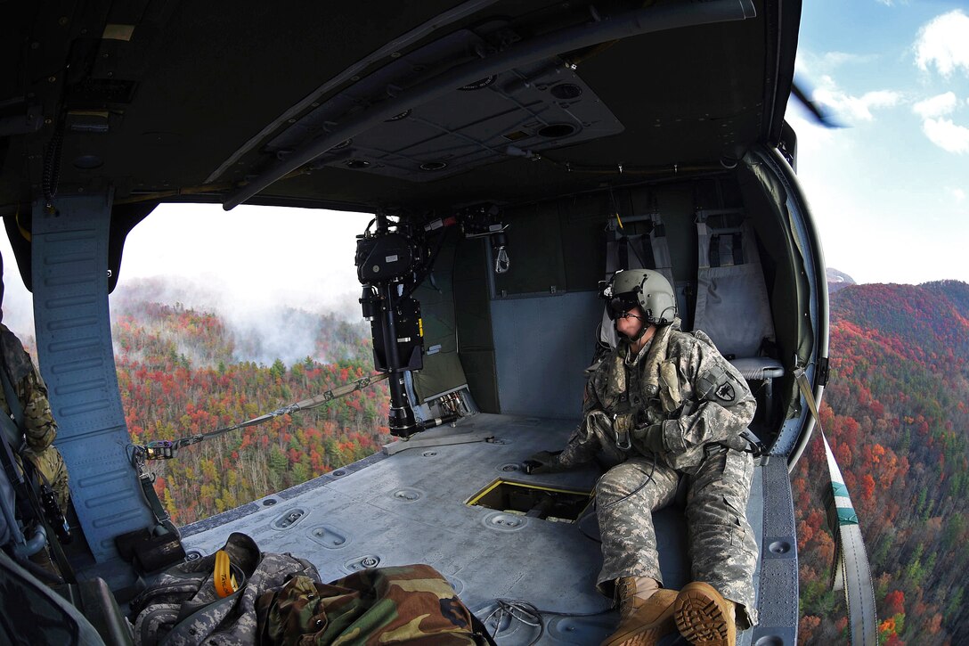 Army crew chiefs sit inside a UH-60 Black Hawk helicopter after releasing water from a bucket firefighting system during a wildfire fighting mission near Table Rock, S.C., Nov. 24, 2016. Army National Guard photo by Staff Sgt. Roberto Di Giovine