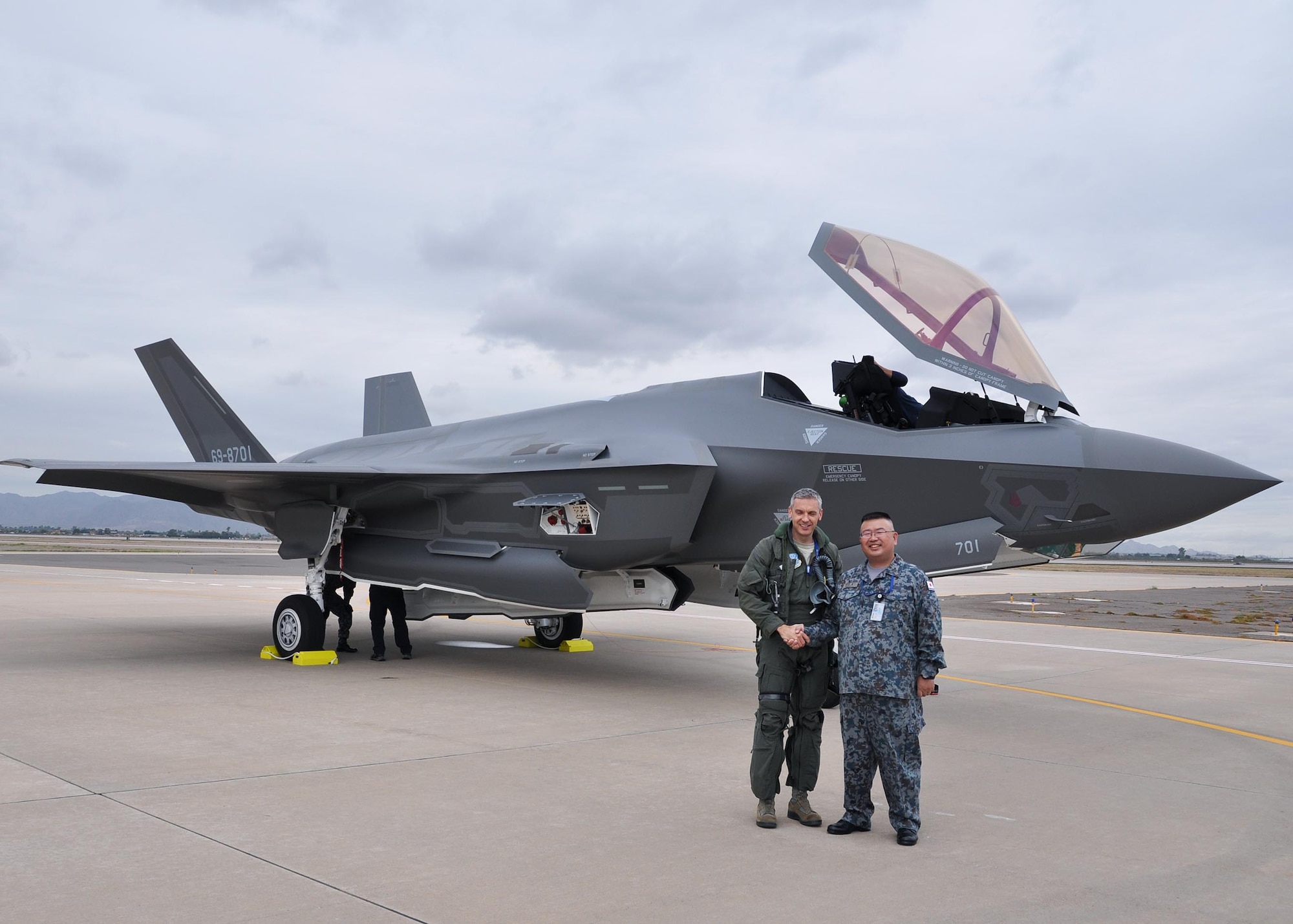 Maj. Toru Tsuchiya, Japan Air Self-Defense Force, Japanese F-35A foreign liaison officer and Lt. Col. Todd Lafortune, Defense Contract Management Agency Lockheed Martin, F-35 acceptance pilot, shake hands Nov. 28 during the arrival of the first Foreign Military Sales F-35 at Luke Air Force Base, Ariz. (U.S. Air Force photo by Tech. Sgt. Louis Vega Jr.)