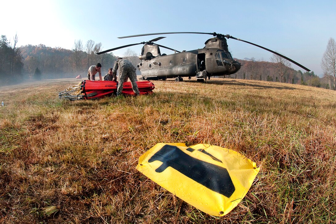 Soldiers prepare a bucket firefighting system to be connected underneath their CH-47 Chinook helicopter which will be used to release water during a wildfire fighting mission near Table Rock, S.C., Nov. 24, 2016. The soldiers and helicopters are assigned to the South Carolina Army National Guard’s 59th Aviation Troop Command, and provided support on Thanksgiving Day. Army National Guard photo by Staff Sgt. Roberto Di Giovine