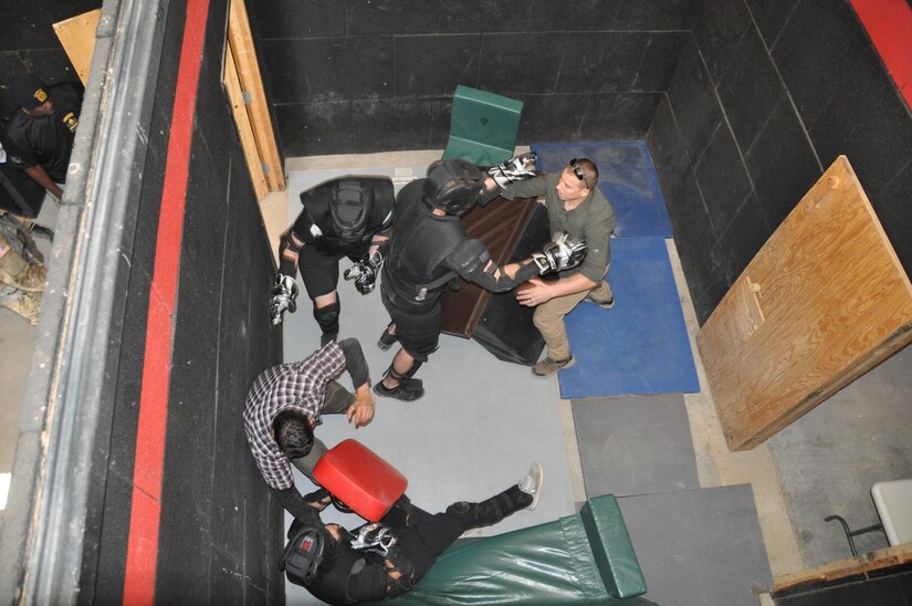 Pvt. Juan Garcia, Pvt. Stephen Chaney and Pfc. Devon Tankersley, dressed in black, all infantry Soldiers assigned to 1st Battalion, 35th Armor Regiment, 2nd Brigade Combat Team, 1st Armored Division, pose as intruders and begin to fight with Sgt. Cesar Medina, right, and Sgt. Ryan Hernandez, left, assigned to Company B, 410th Civil Affairs Battalion, U.S. Army Reserve, during close-quarters combat training at McGregor Range, N.M., Nov. 19, 2016.