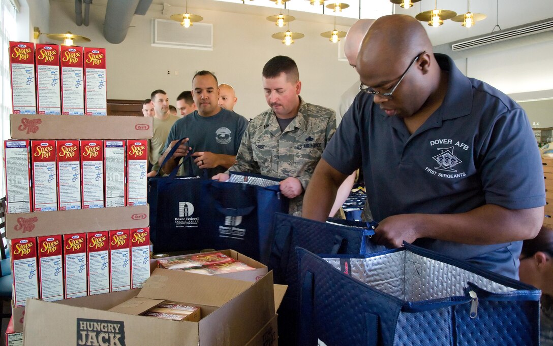 Leading the food basket assembly line, Master Sgts. Montrell Jones, 436th Logistics Readiness Squadron; Tony Christ, 436th Operations Support Squadron; and Juan DeJesus, 436th Aircraft Maintenance Squadron, first sergeants, fill Thanksgiving holiday food baskets with food items Nov. 18, 2016, at the Landings on Dover Air Force Base, Del. Food items were placed in reusable thermal grocery bags donated by the Dover Federal Credit Union. (U.S. Air Force photo by Roland Balik)