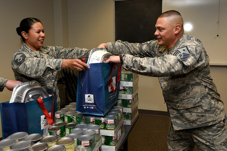 PETERSON AIR FORCE BASE, Colo. – Master Sgt. Jenet Shaffner, 561st Network Operations Squadron, passes a bag full of Thanksgiving food items to Master Sgt. Roger Davila, 561st Network Operations Squadron first sergeant, at the base chapel on Peterson Air Force Base, Colo., Nov. 21, 2016. The Peterson first sergeants put together Thanksgiving baskets for Airmen who needed assistance during the holiday. (U.S. Air Force photo by Senior Airman Rose Gudex)