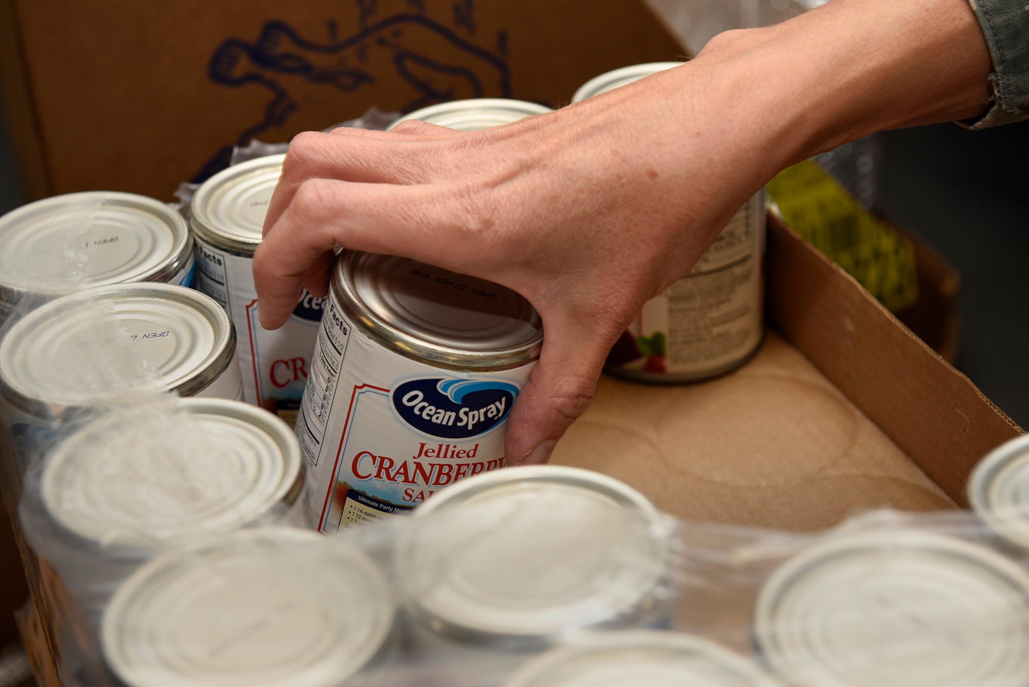 PETERSON AIR FORCE BASE, Colo. - A Peterson first sergeant grabs a can of cranberry sauce to add to a bag of Thanksgiving goodies at the base chapel on Peterson Air Force Base, Colo., Nov. 21, 2016. Peterson first sergeants gathered to fill Thanksgiving baskets to deliver to Airmen who needed assistance during the holiday. (U.S. Air Force photo by Senior Airman Rose Gudex)