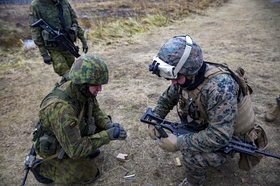 A U.S. Marine and a Latvian soldier help each other load ammunition to prepare for a live-fire range during Exercise Iron Sword 16 at the Rukla Training Area, Rukla, Lithuania, Nov. 23, 2016. The Marine is assigned to Black Sea Rotational Force 16.2. Iron Sword is an annual multinational exercise designed to enhance interoperability between NATO allies who are dedicated to ensuring a safe and secure Europe. Marine Corps photo by Cpl. Clarence L. Wimberly