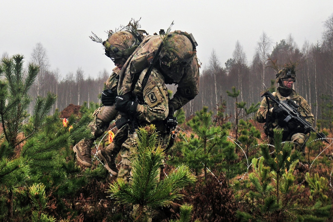 A paratrooper carries a mock-wounded comrade during Exercise Iron Sword 2016 in Pabrade, Lithuania, Nov. 24, 2016. Army photo by Staff Sgt. Corinna Baltos