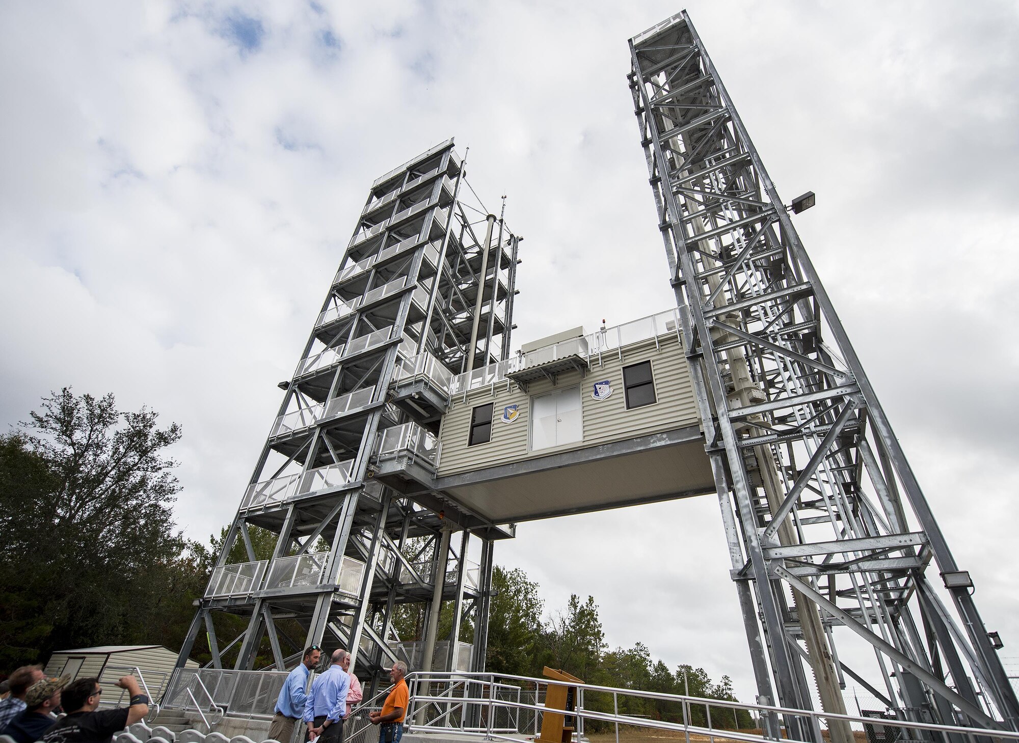 The Air Force Research Lab Munitions Directorate’s variable height tower begins its ascent as people watch Nov. 29 at Eglin Air Force Base, Fla.  A ribbon cutting ceremony was held for the new structure located on Eglin’s range.  The new capability enables researchers at the C-86 range to take improved sensor data because it reduces signal interferences caused by the warmer air and objects near the ground. (U.S. Air Force photo/Samuel King Jr.)