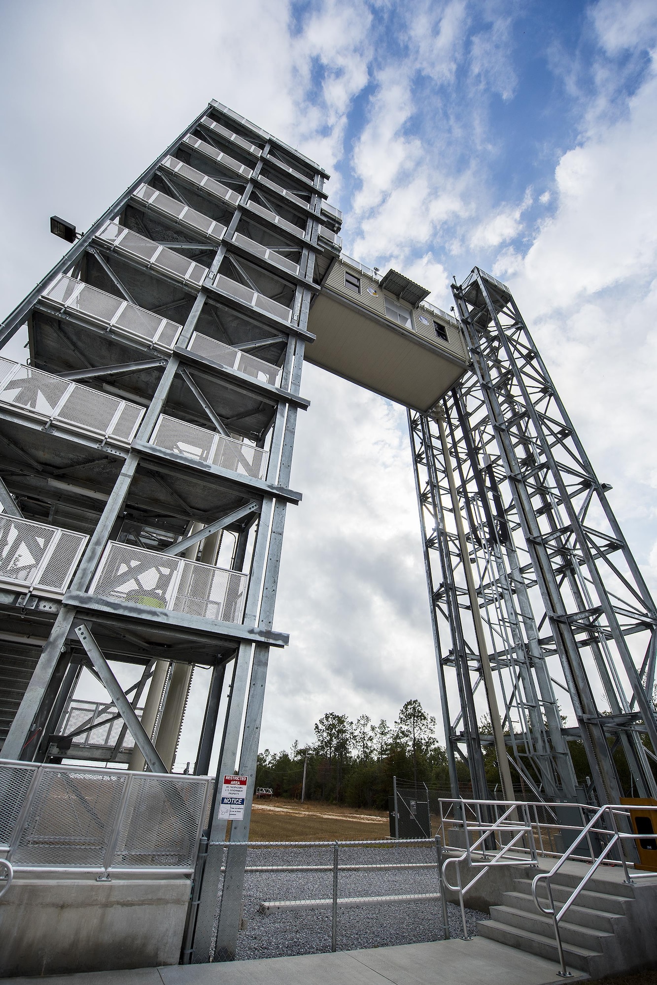 The Air Force Research Lab Munitions Directorate’s variable height tower reaches its top as people watch Nov. 29 at Eglin Air Force Base, Fla.  A ribbon cutting ceremony was held for the new structure located on Eglin’s range.  The new capability enables researchers at the C-86 range to take improved sensor data because it reduces signal interferences caused by the warmer air and objects near the ground. (U.S. Air Force photo/Samuel King Jr.)