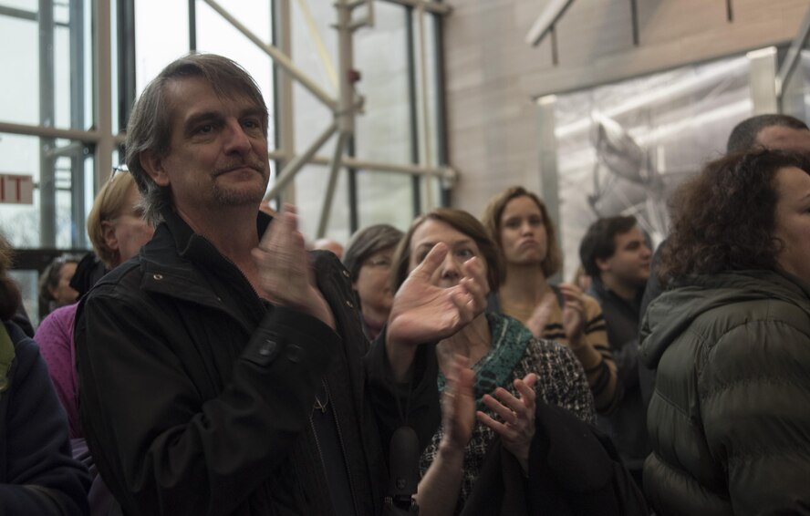 Retired Senior Master Sgt. Bob Thurston, former U.S. Air Force Band member, applauds during a U.S. Air Force Band performance at the Smithsonian National Air and Space Museum in Washington, D.C., Nov. 29, 2016. Members of the U.S. Air Force Band, with help from their sister unit the U.S. Air Force Honor Guard, kicked off the holiday season by surprising visitors at the museum with a Flash Mob experience. Thurston retired from the band in 2014 and has arranged the music for all four of the flash mobs performed by the U.S. Air Force Band.  (U.S. Air Force photo by Airman 1st Class Rustie Kramer) 