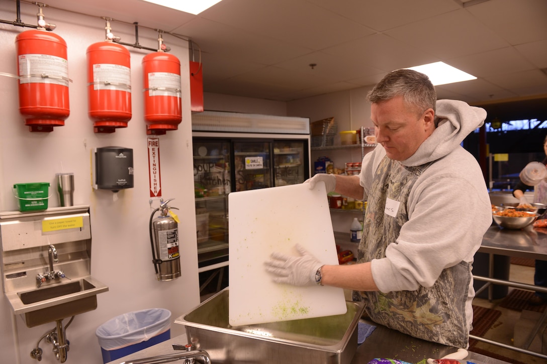 Coast Guard Cmdr. James Binniker prepares food while volunteering at the Downtown Soup Kitchen Hope Center in Anchorage, Alaska, Nov. 29, 2016. Binniker is a assigned to Coast Guard Sector Anchorage. Binniker and other Sector Anchorage members helped prepare food and care packages for the homeless. Coast Guard photo by Petty Officer 1st Class Bill Colclough.